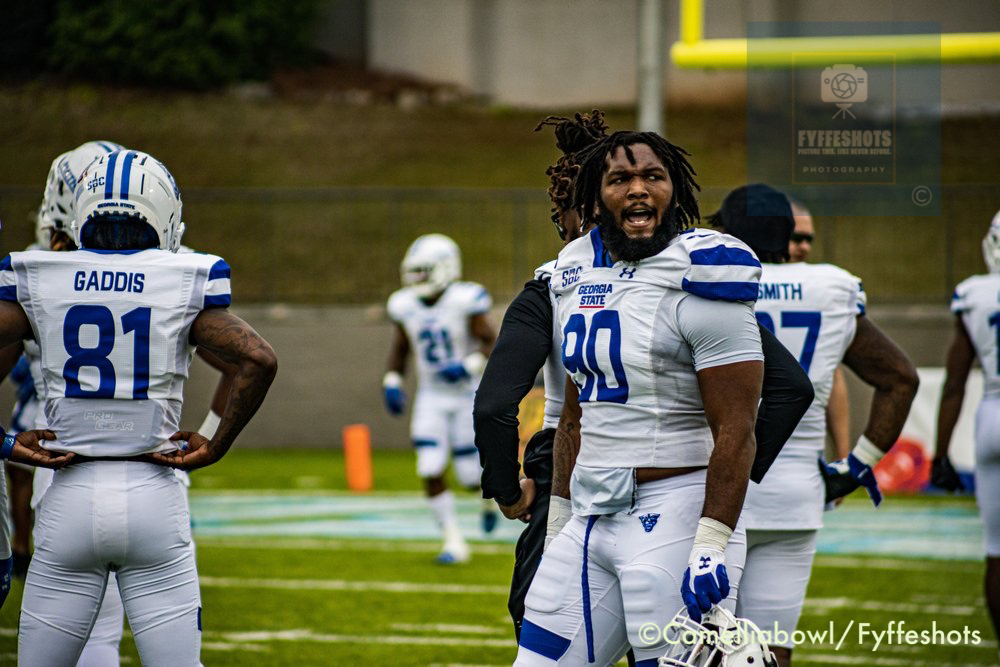 Georgia State football players in white and blue uniforms on the field during a game, including linebacker wearing number 90.