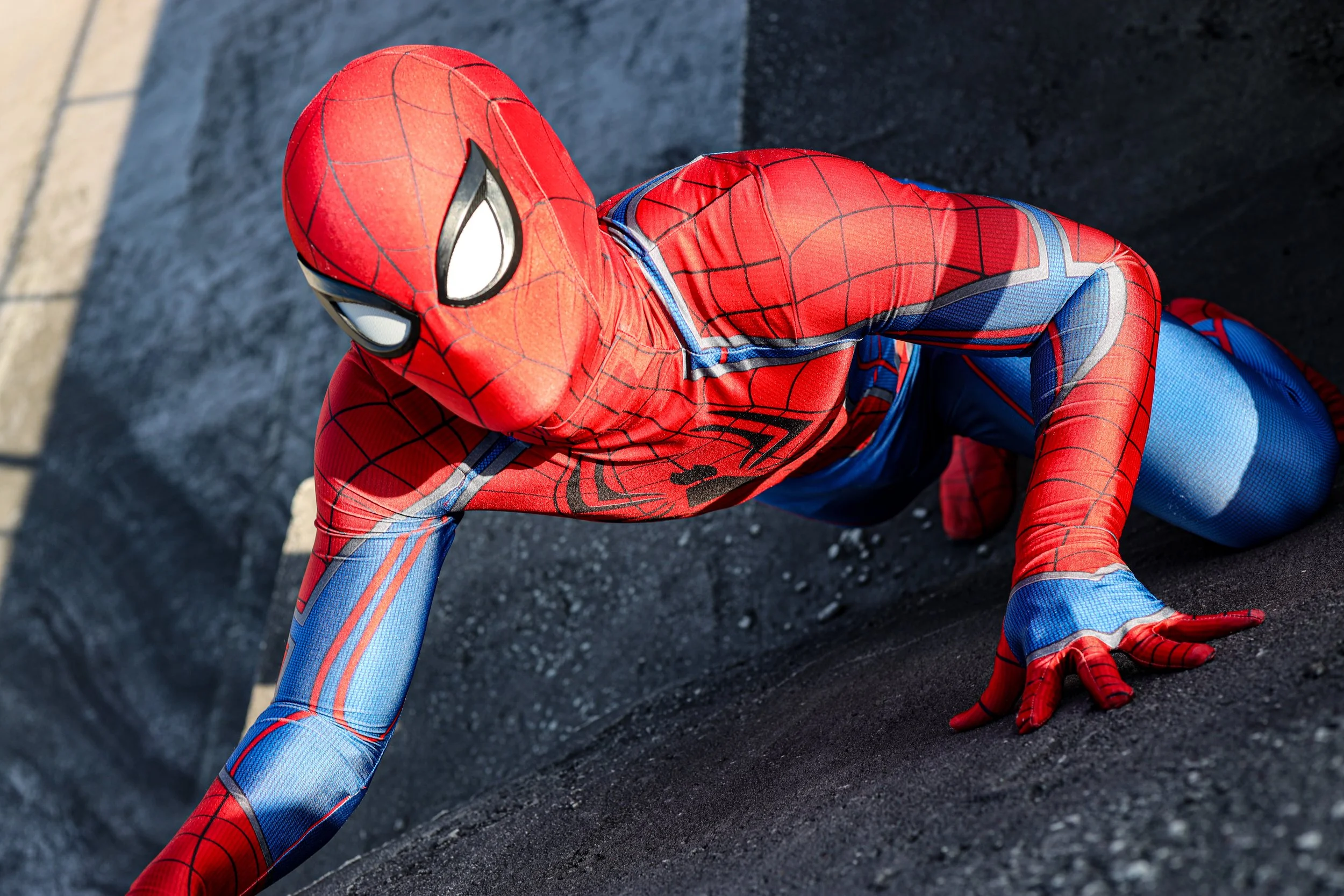 Person in a red and blue Spider-Man costume climbing on a rooftop