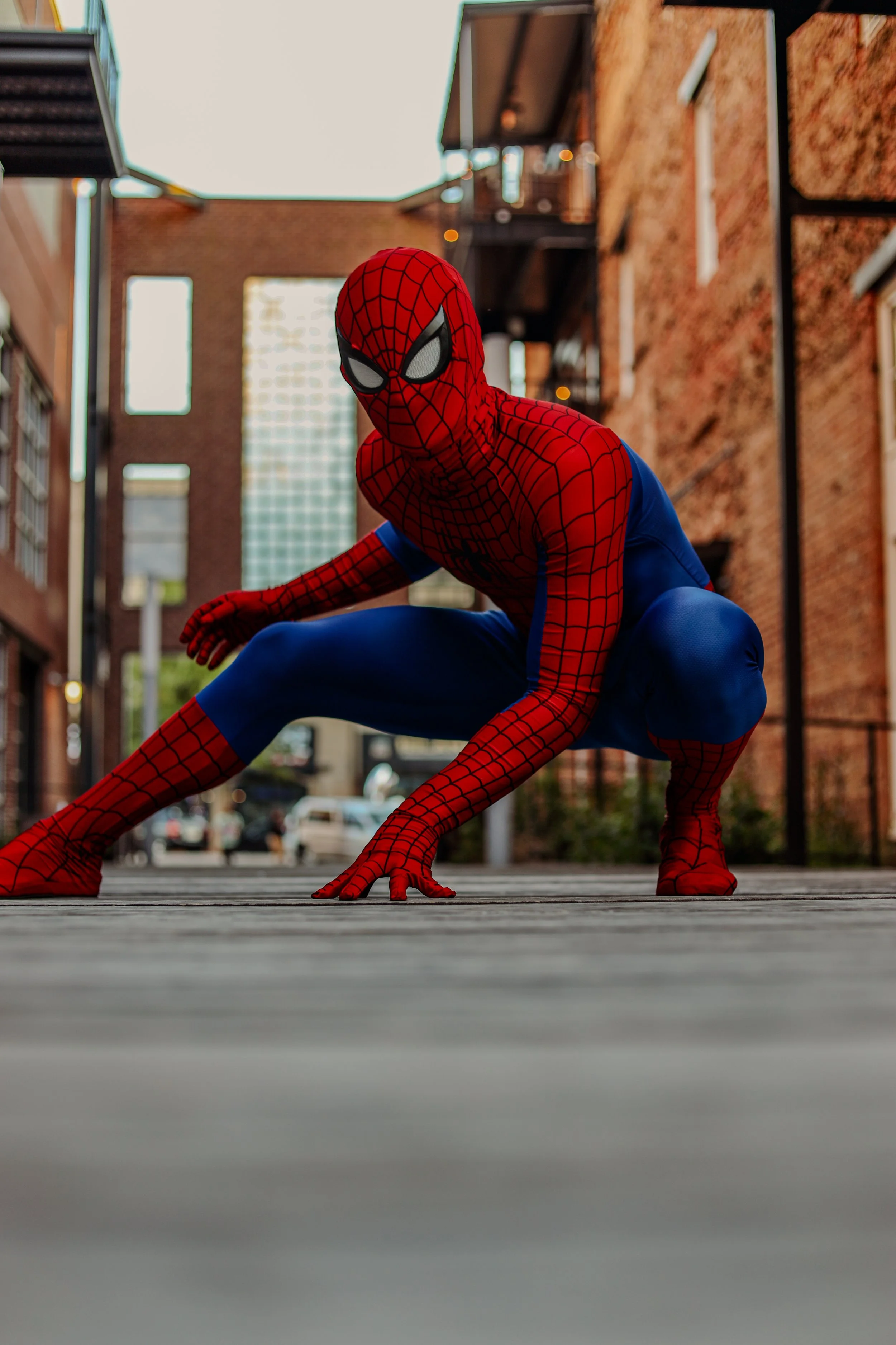 Spider-Man in a red and blue web-patterned suit crouching on a city street