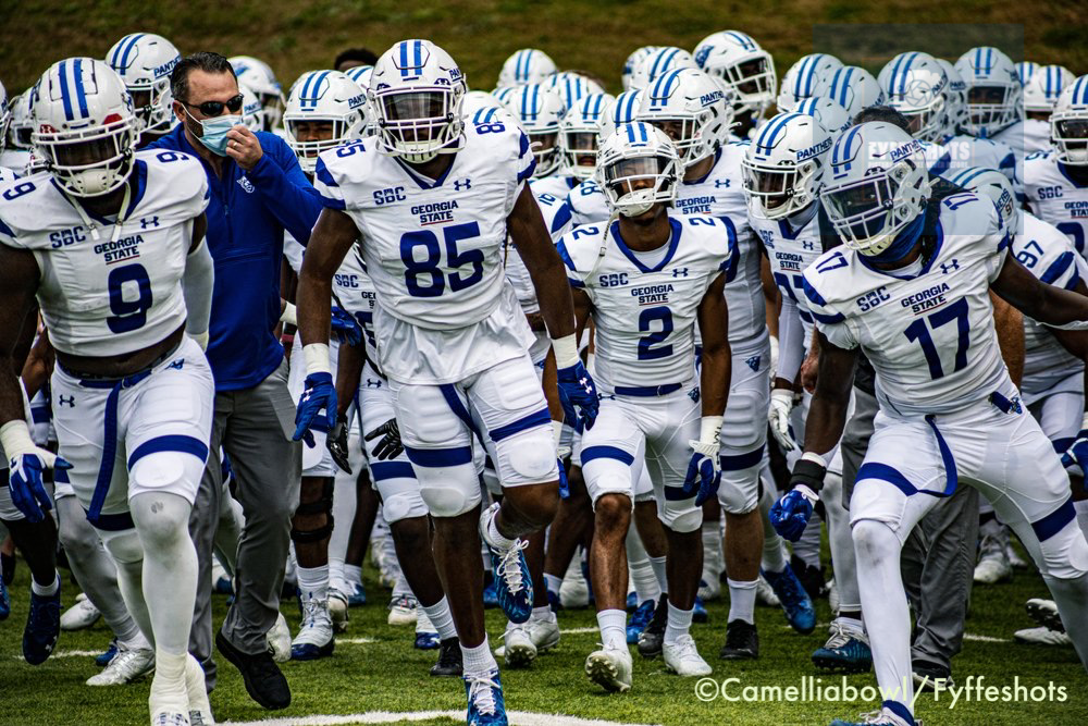 Georgia State Panthers football players in white and blue uniforms run onto the field before a game.