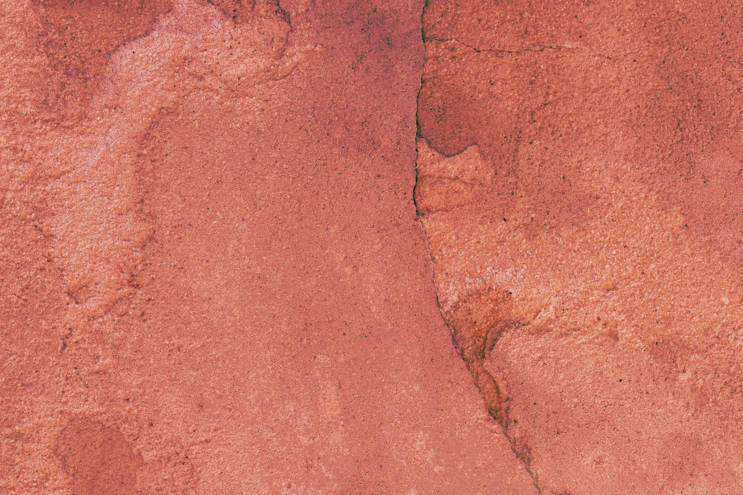 Surface en béton rouge fissurée.