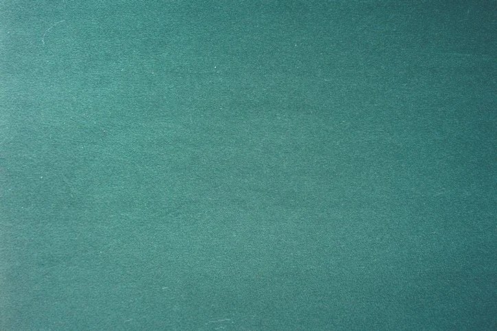 Une surface en papier ou en tissu vert foncé avec une texture légèrement granulée.