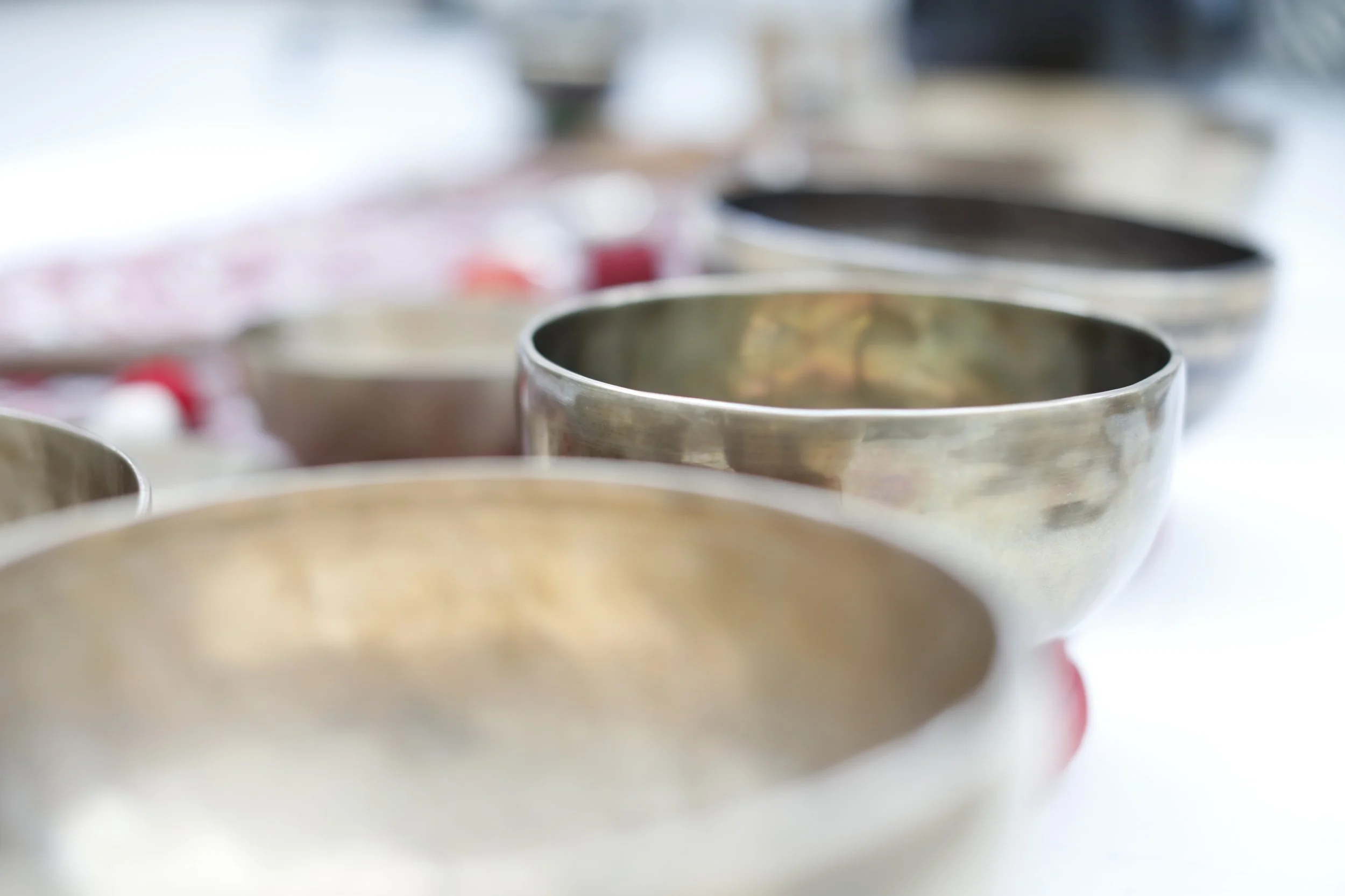 Plusieurs bols en métal alignés sur une table, certains contiennent des liquides ou des ingrédients, dans une disposition en ligne