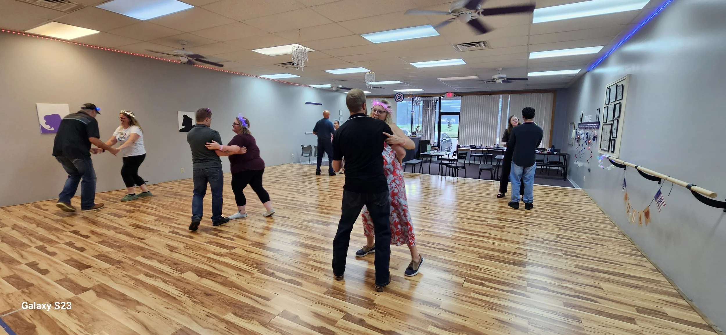 People dancing and socializing in a decorated indoor community center or hall.