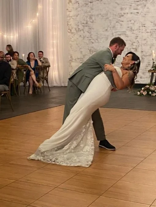 A newlywed couple dancing, with the groom dipping the bride on the dance floor.