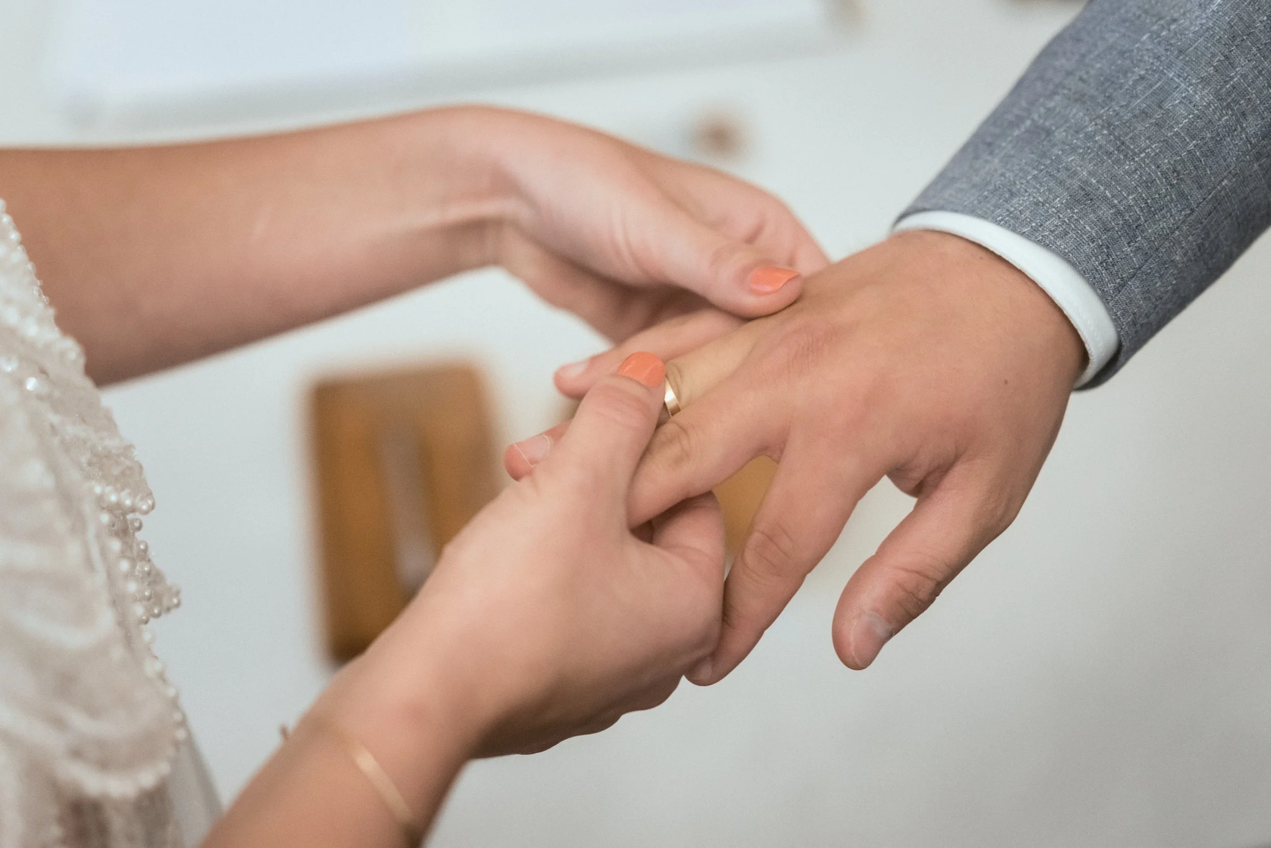 Nahaufnahme einer Hand, die eine andere Hand hält, wahrscheinlich während einer Hochzeitszeremonie.