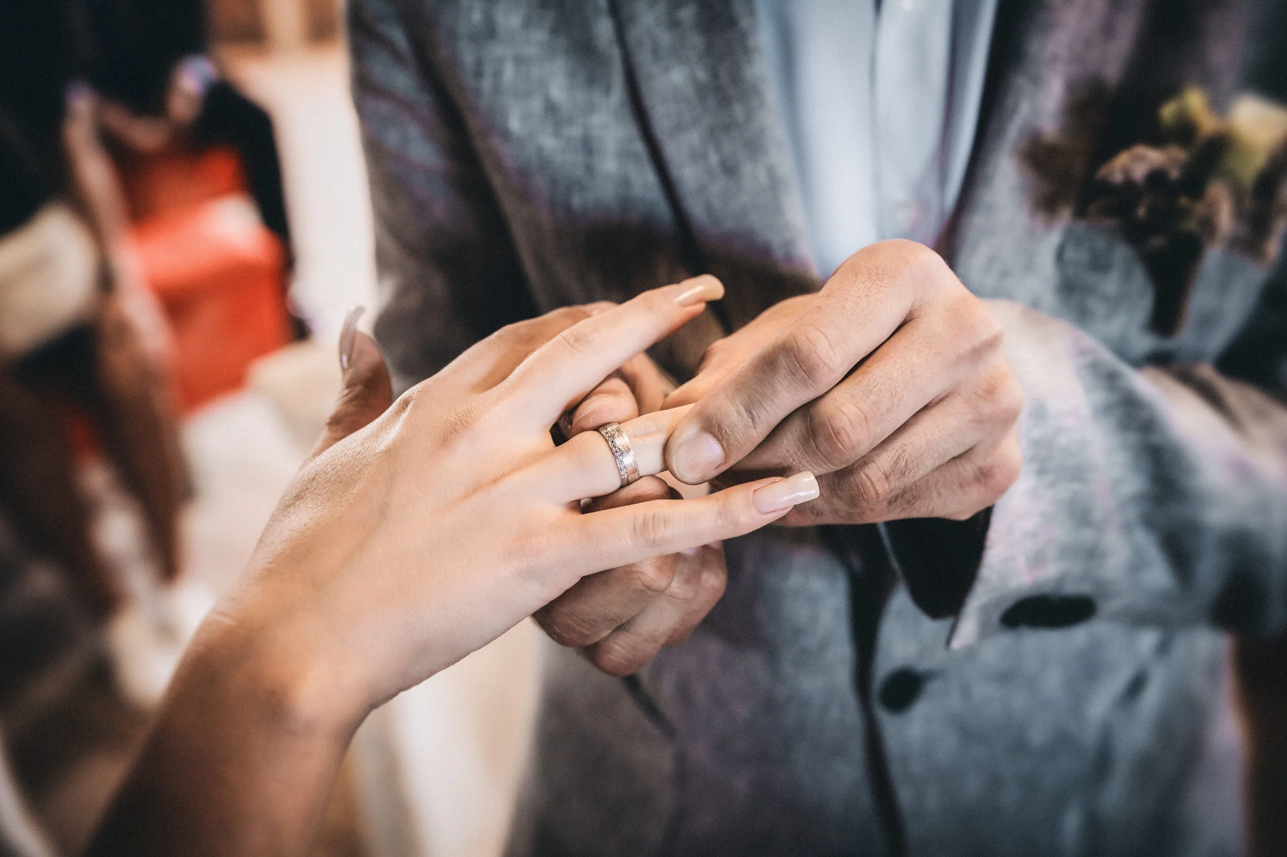 Nahaufnahme von einem Paar, das sich bei einer Hochzeit die Hände hält, das Brautpaar trägt Ringe.