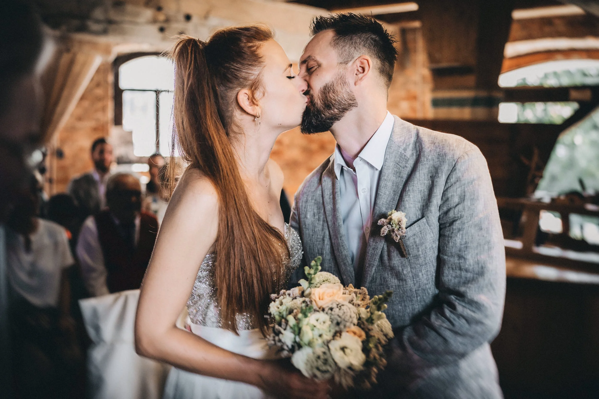 Ein Brautpaar beim Hochzeitstanz in einem rustikalen Raum mit Holzdecken und großen Fenstern.