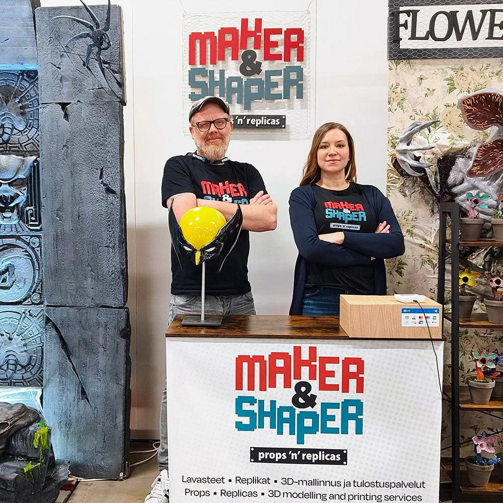 Maker & Shaper team standing behind their exhibition booth with handmade art and design pieces.
