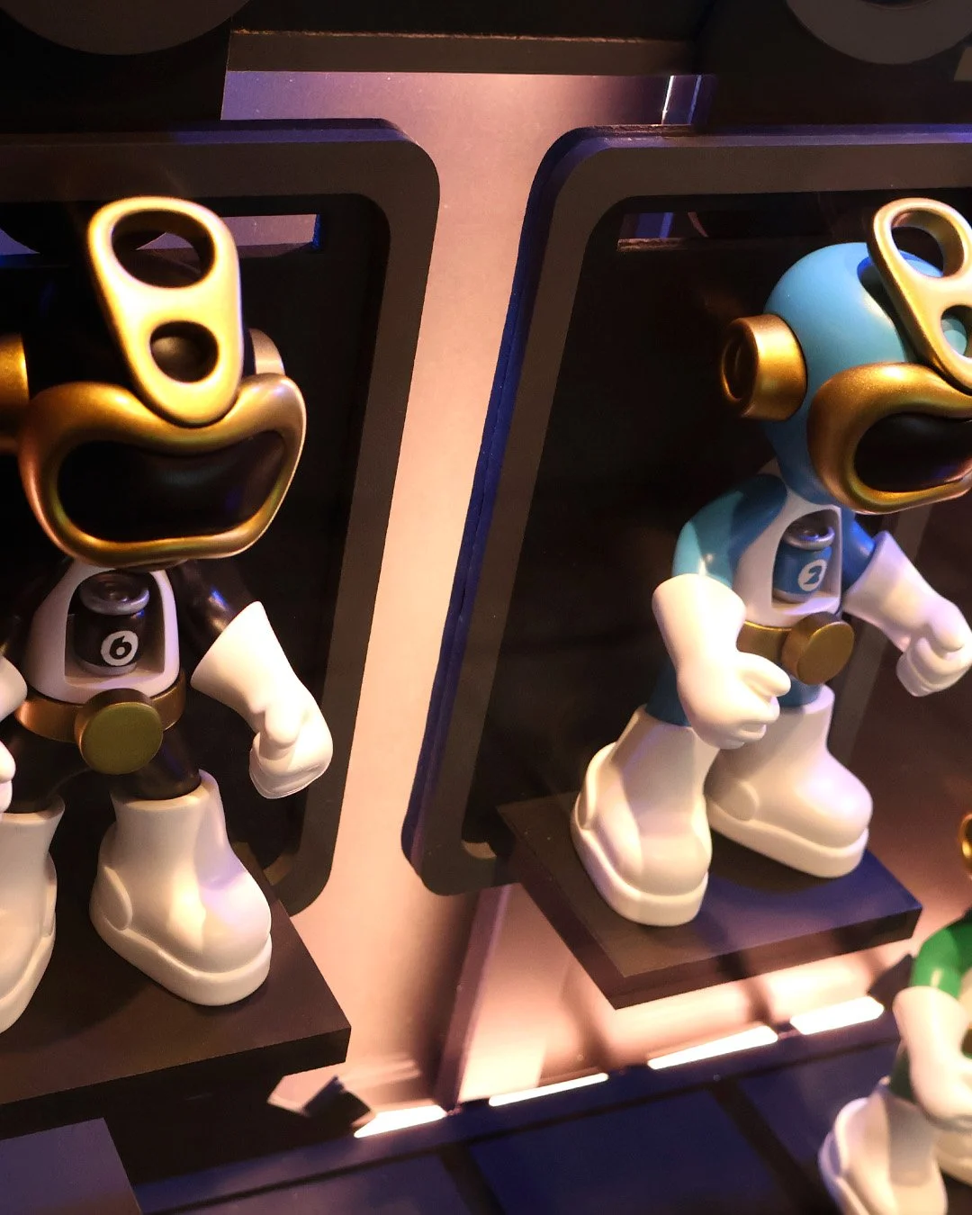 Two vinyl figurines of the power ranger art toy , numbered 6 and 2, displayed on black platforms with black backdrops.