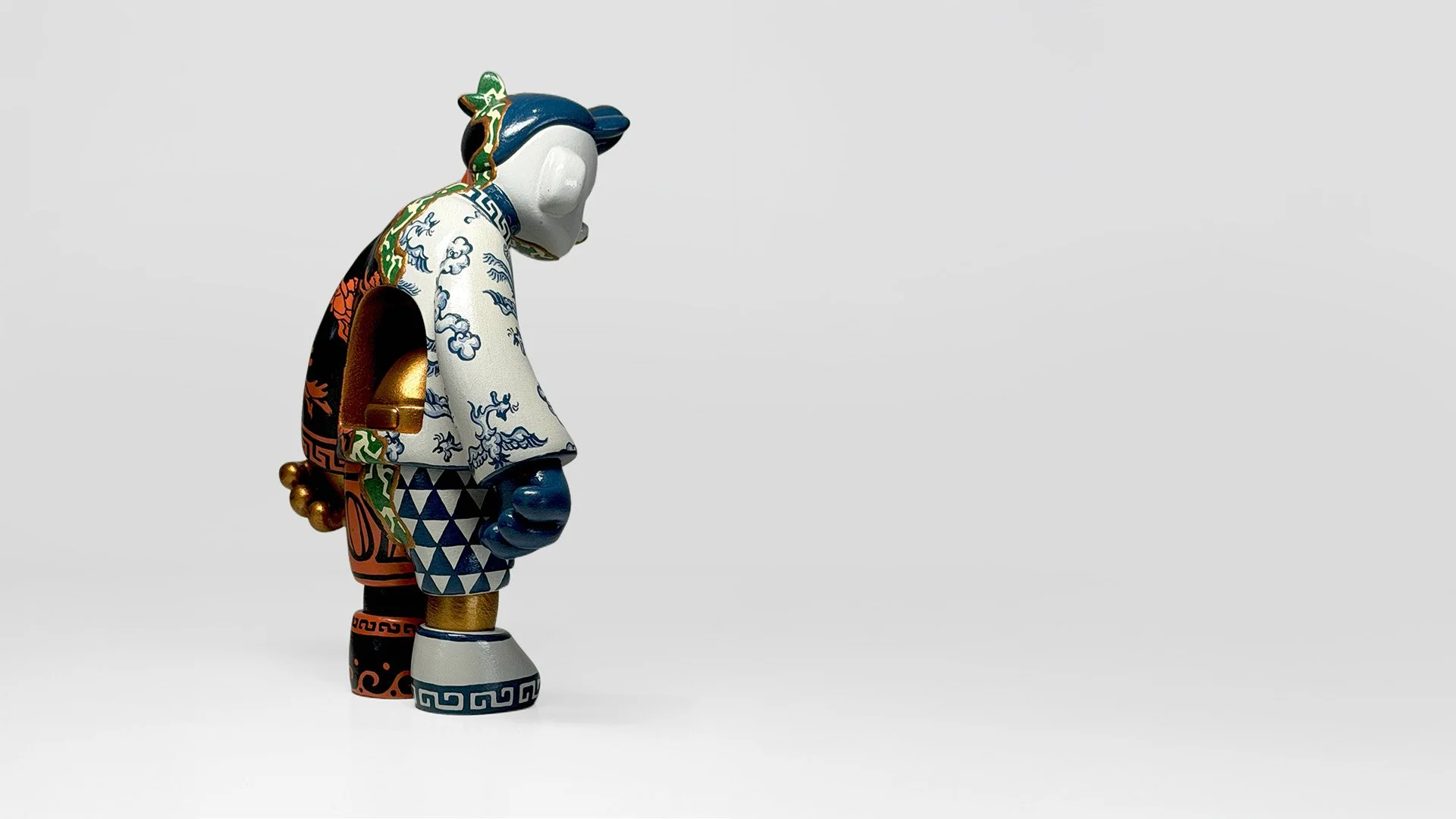 Joyboy art toy by Yoshihito, featuring a bowed figure decorated with intricate blue, green, orange and gold patterns against a light grey background.