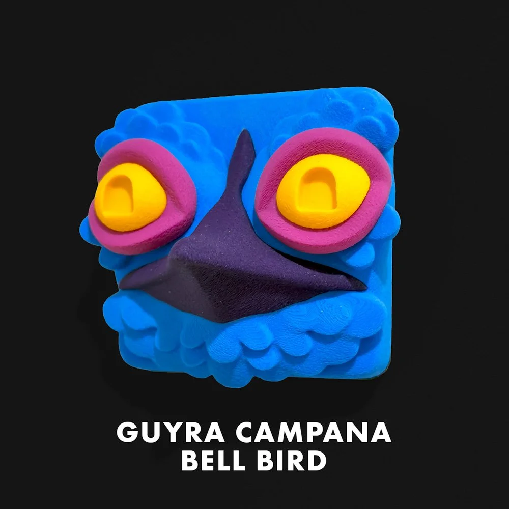 Colorful clay sculpture of a bird with yellow eyes, purple beak, and a blue face, labeled 'Guyra Campana Bell Bird'.