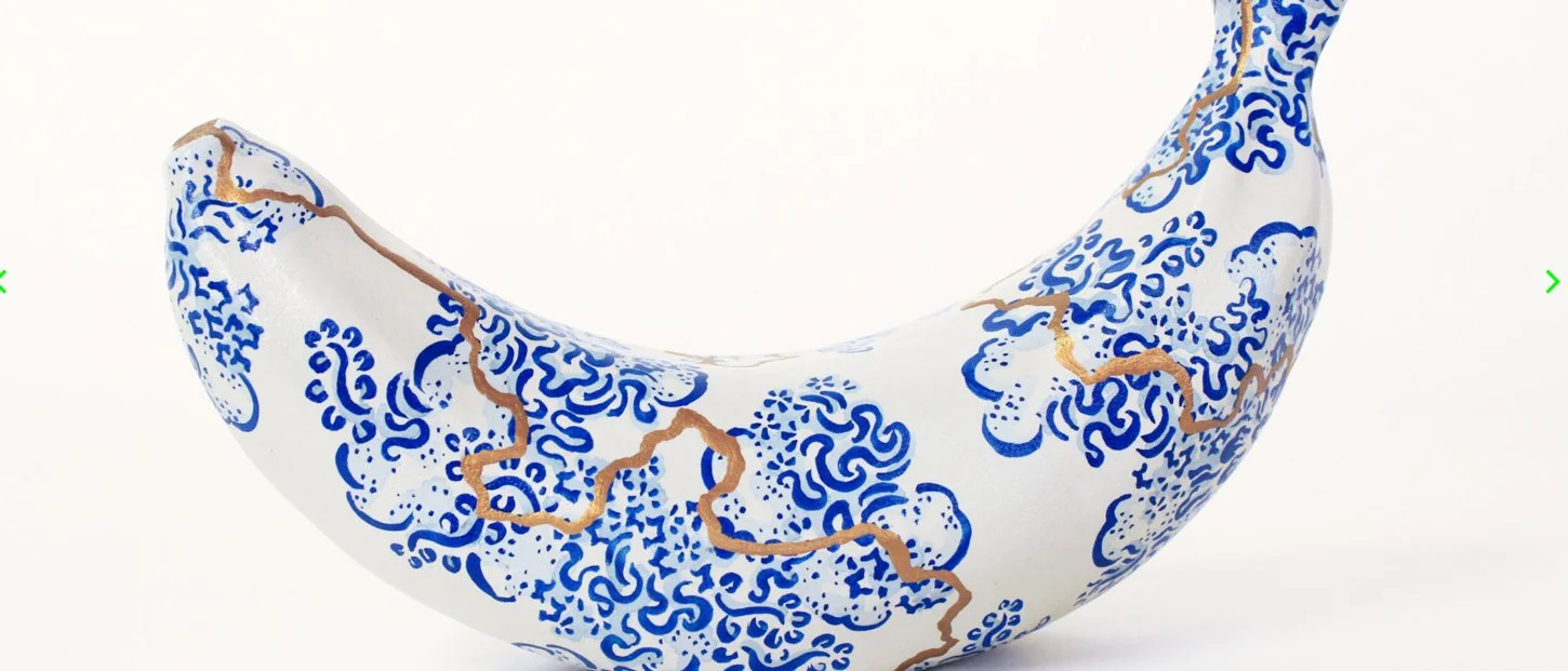 Decorative crescent-shaped ceramic sculpture with blue and gold patterns on a white background.