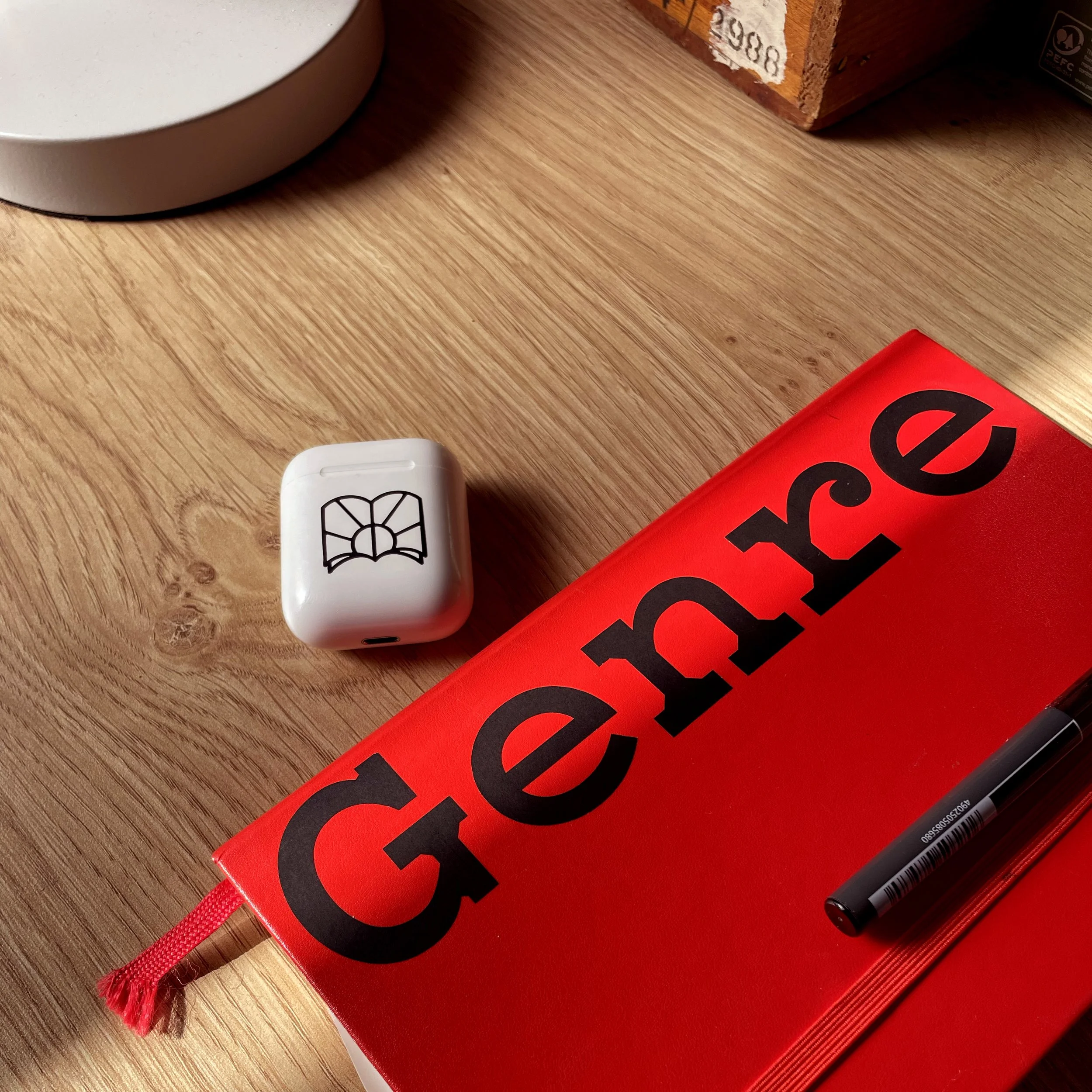 A red notebook branded with the word Genre
