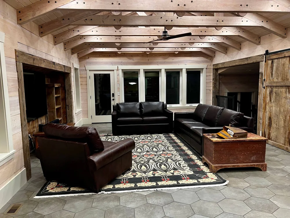 Covered outdoor living room with exposed beams and a stone floor, built by Bergeson Construction