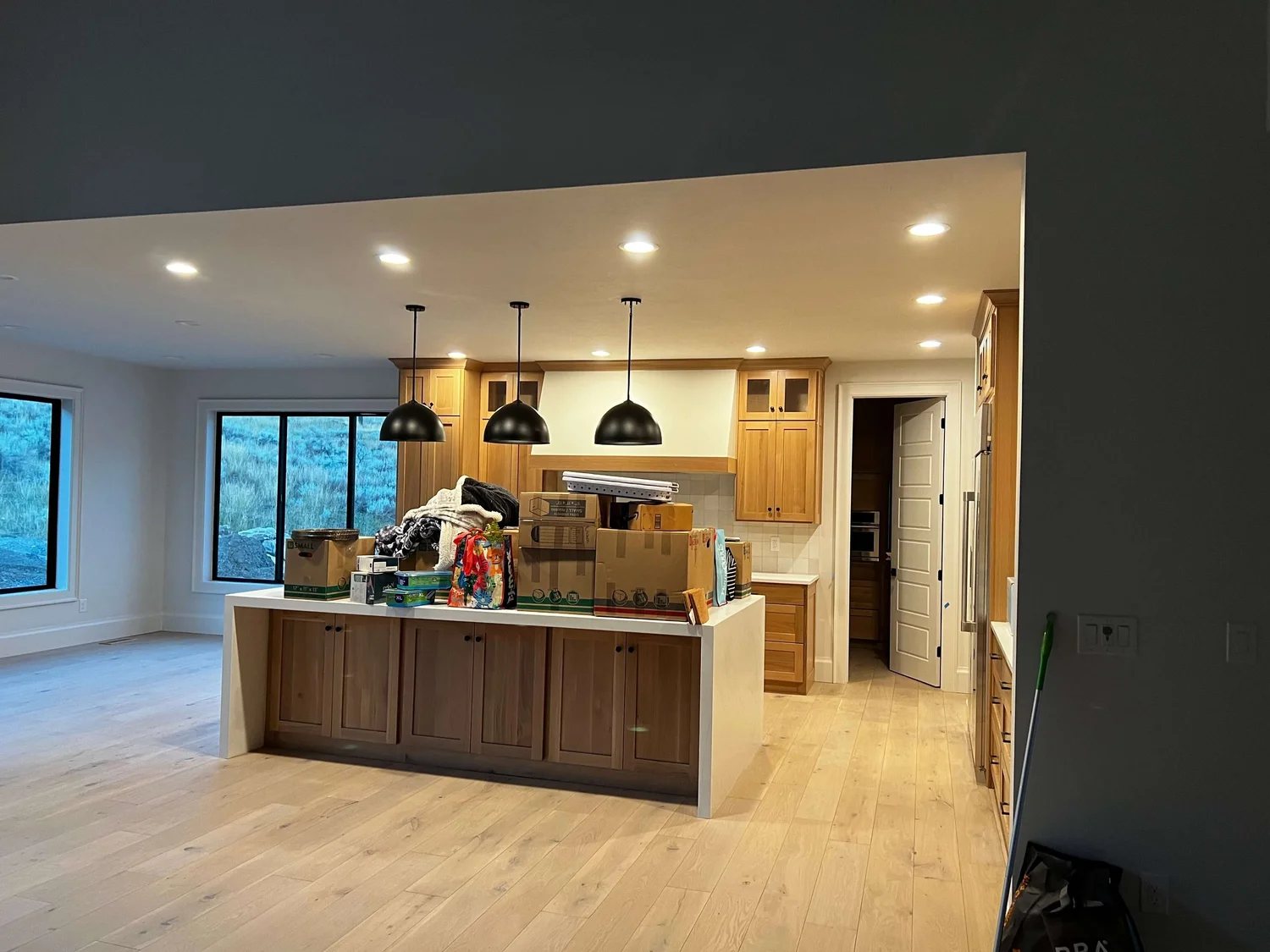 Kitchen remodel nearing completion with white oak floors, a stained wood island and pendant lighting, built by Bergeson Construction in Cache Valley, Utah