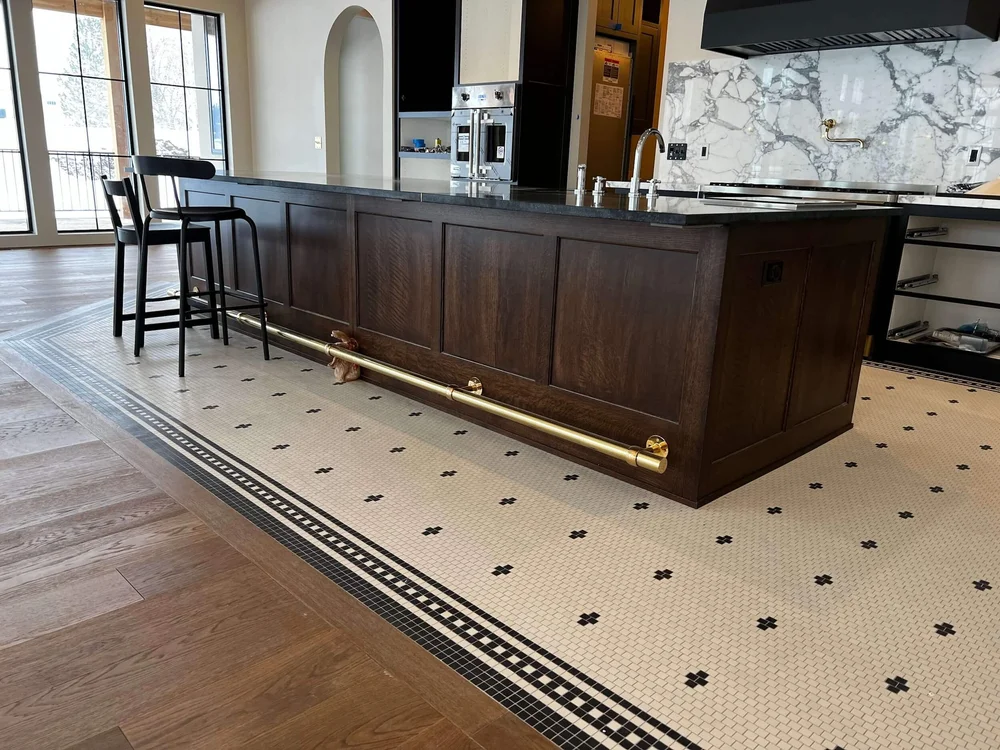 Kitchen with a long walnut island, marble backsplash and patterned tile floor by Bergeson Construction