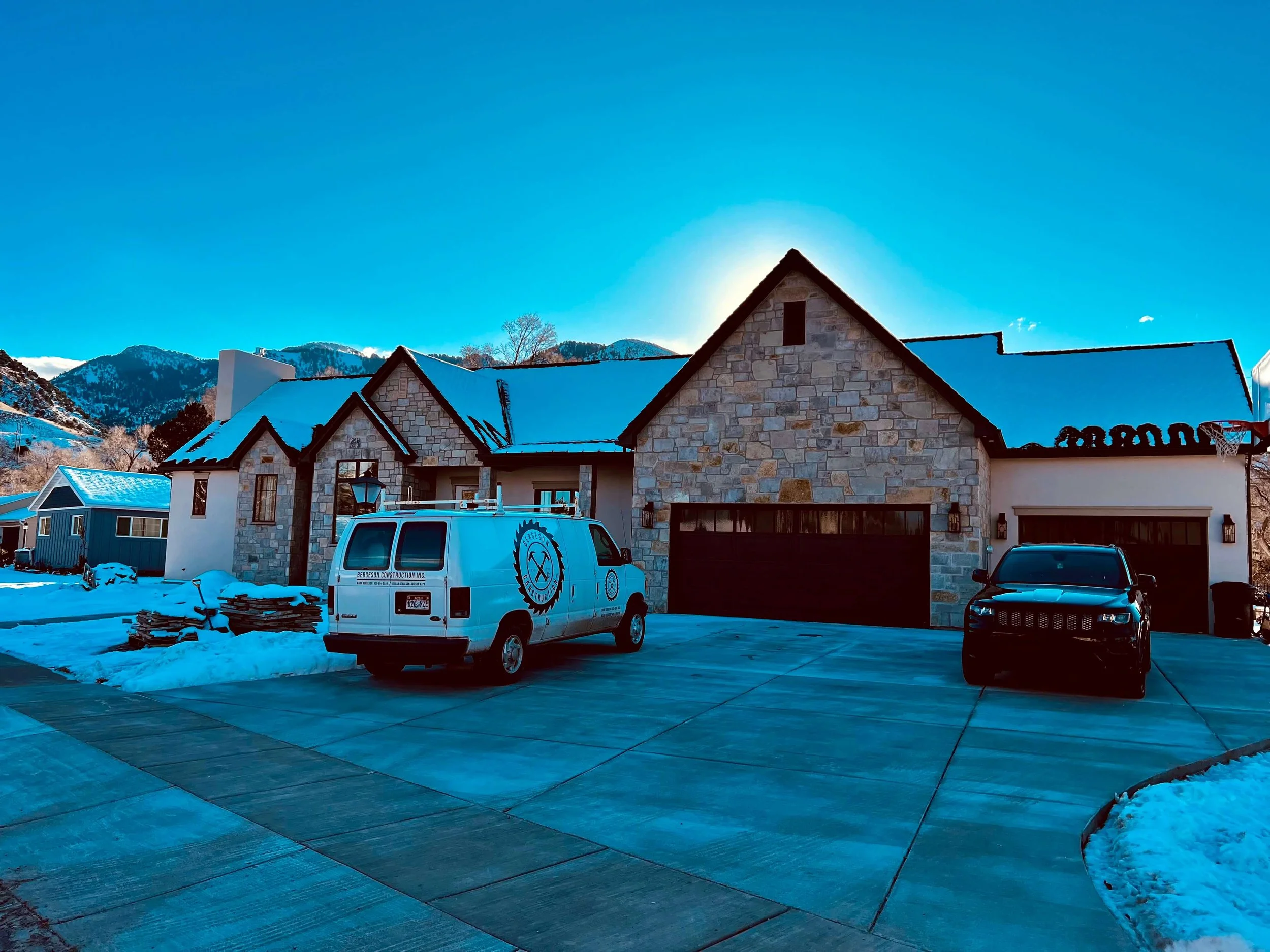 Custom home with a stone gable and snow-covered roof against the Cache Valley mountains, built by Bergeson Construction in Logan, Utah