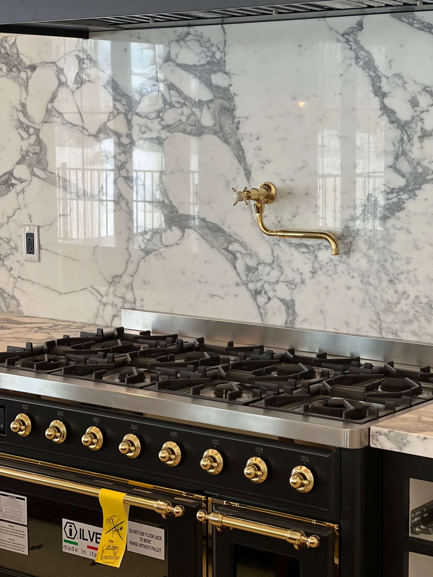 Full-height marble slab behind a professional range with a pot filler in a Bergeson Construction kitchen