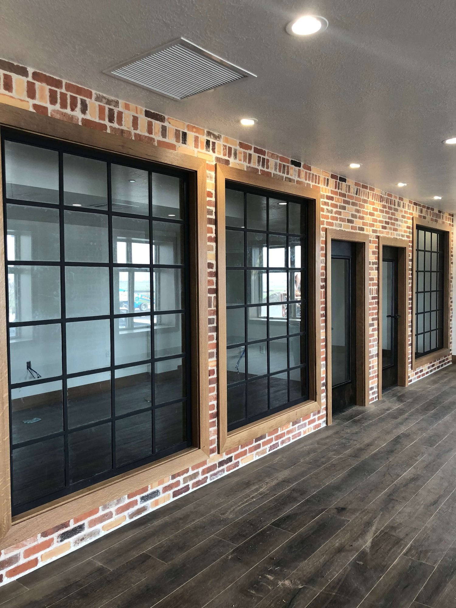 Finished commercial interior with exposed brick, large windows and dark wood flooring, built by Bergeson Construction in Cache Valley, Utah