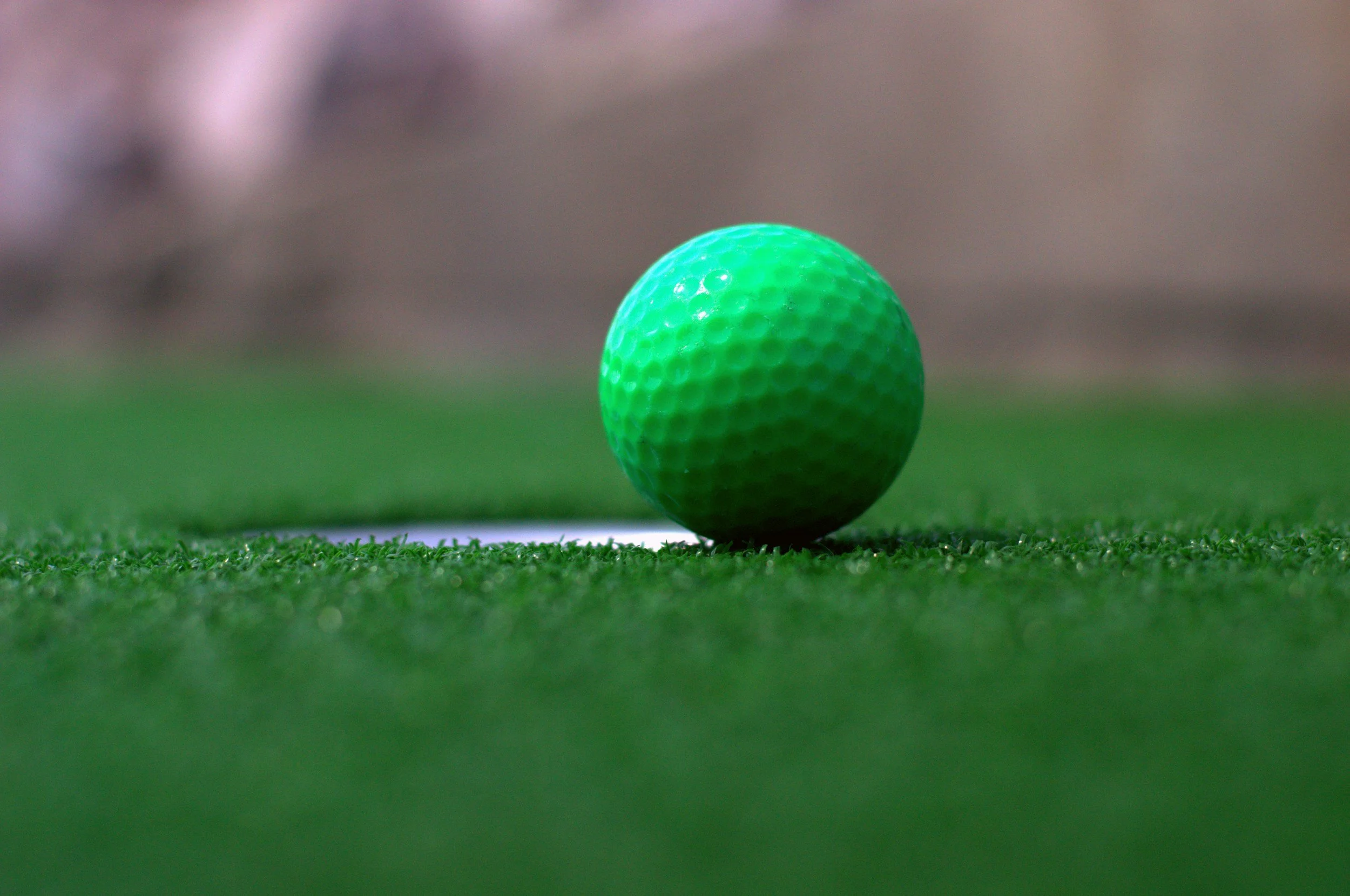 A close-up image of a mobile mini golf golf ball on a green golf course.