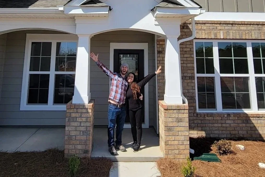 New homeowners celebrating in front of their newly purchased home after closing on a mortgage loan.