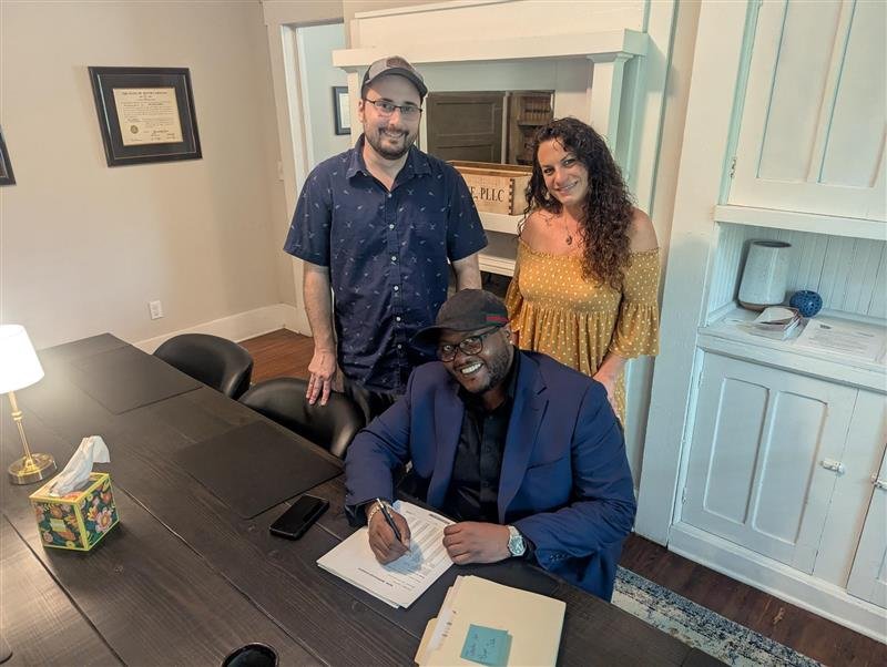 Homebuyers signing closing documents with Realtor Ashley Calla after purchasing a home in North Carolina.
