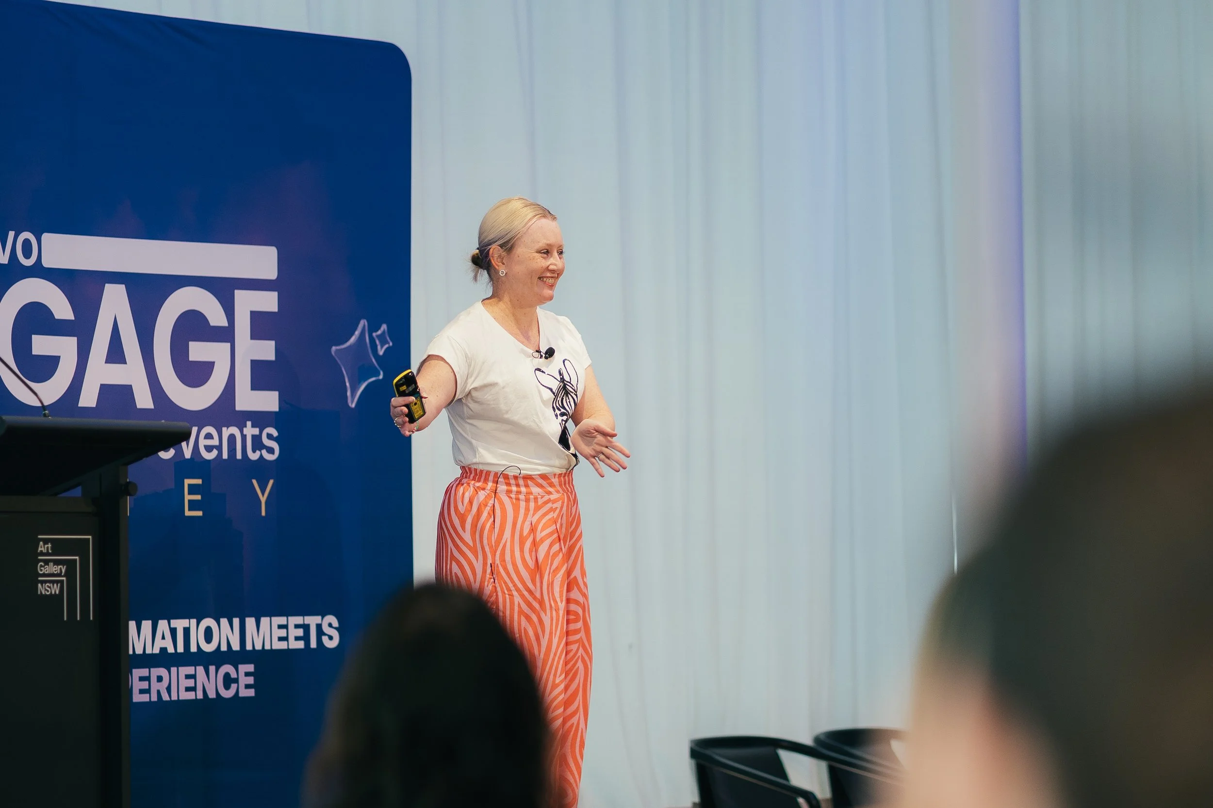 Photo of Mel speaking on a stage at an event