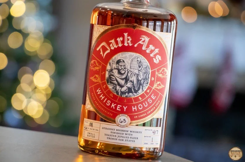 Red labelled Dark Arts French Oak Bourbon bottle on a background of out of focus lights