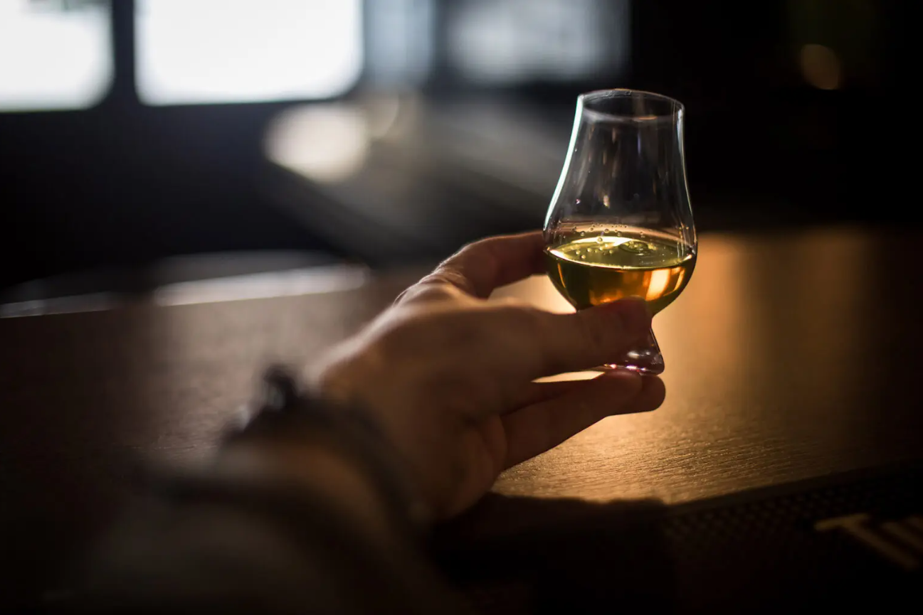 Hand holding Glencairn whisky glass with dark dramatic lighting