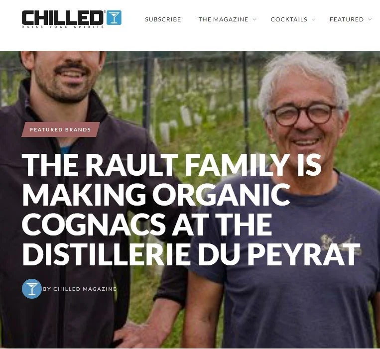 Three men stand in a vineyard in France, two dark-haired sons on either side of white-haired father