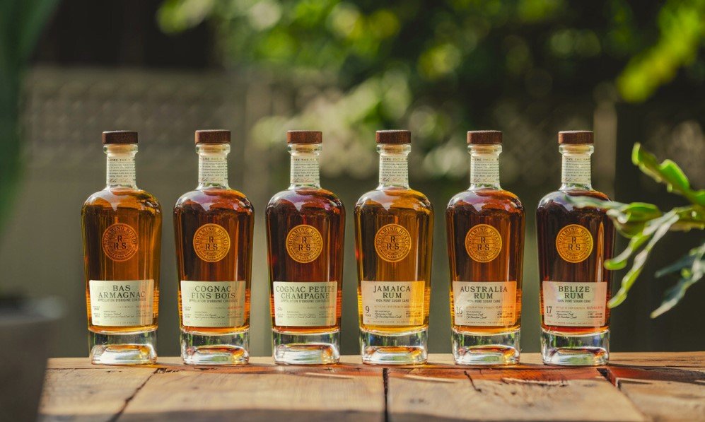 Rum bottles on a wooden table with greenery in the background