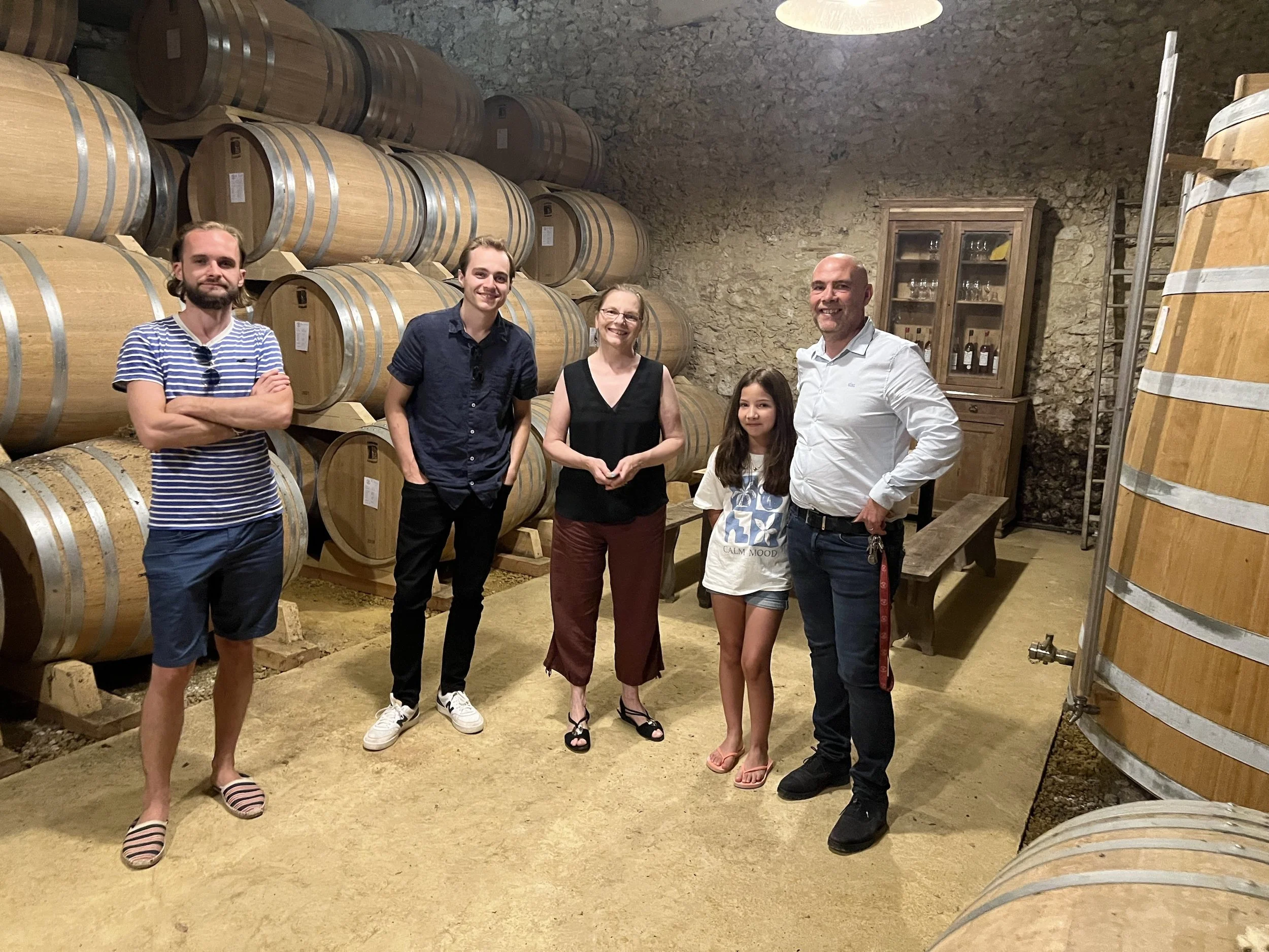 A group of people stand in an aging cellar full of wooden barrels of Armagnac at Armagnac Delord.