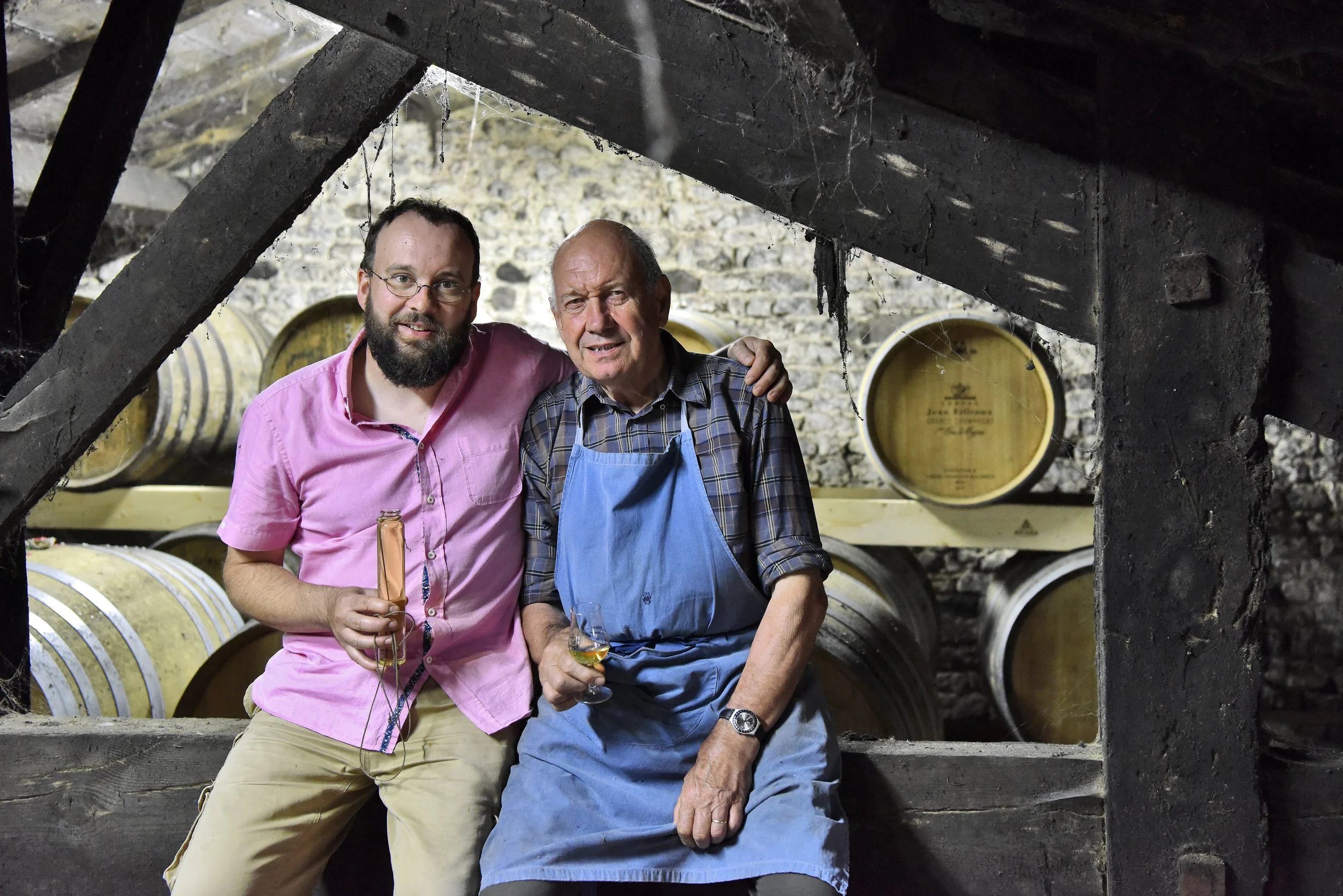 Father and son sit in their family's cognac cellars