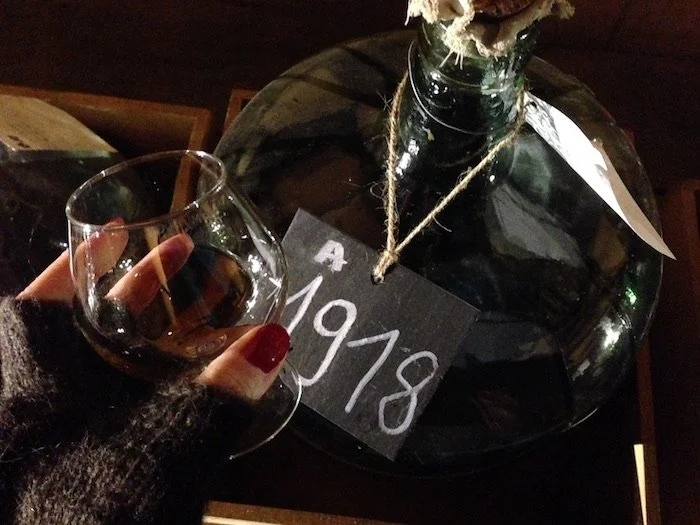 Armagnac glass demijohn labeled 1918 with hand holding glass in front