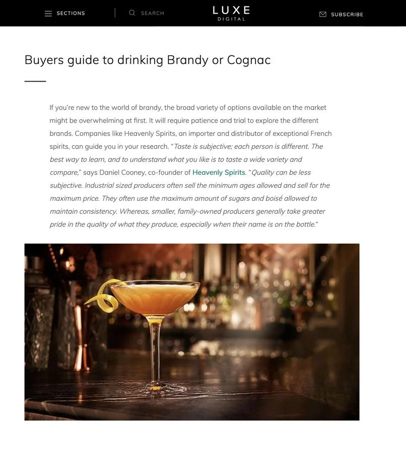 Fancy coupe glass with cocktail and long curlicue lemon peel garnish