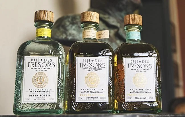 The square rum bottles in front of a metal bust.