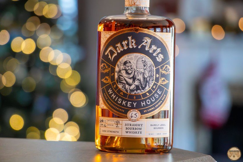 Black labelled Dark Arts Barely Legal Bourbon bottle on a background of out of focus lights