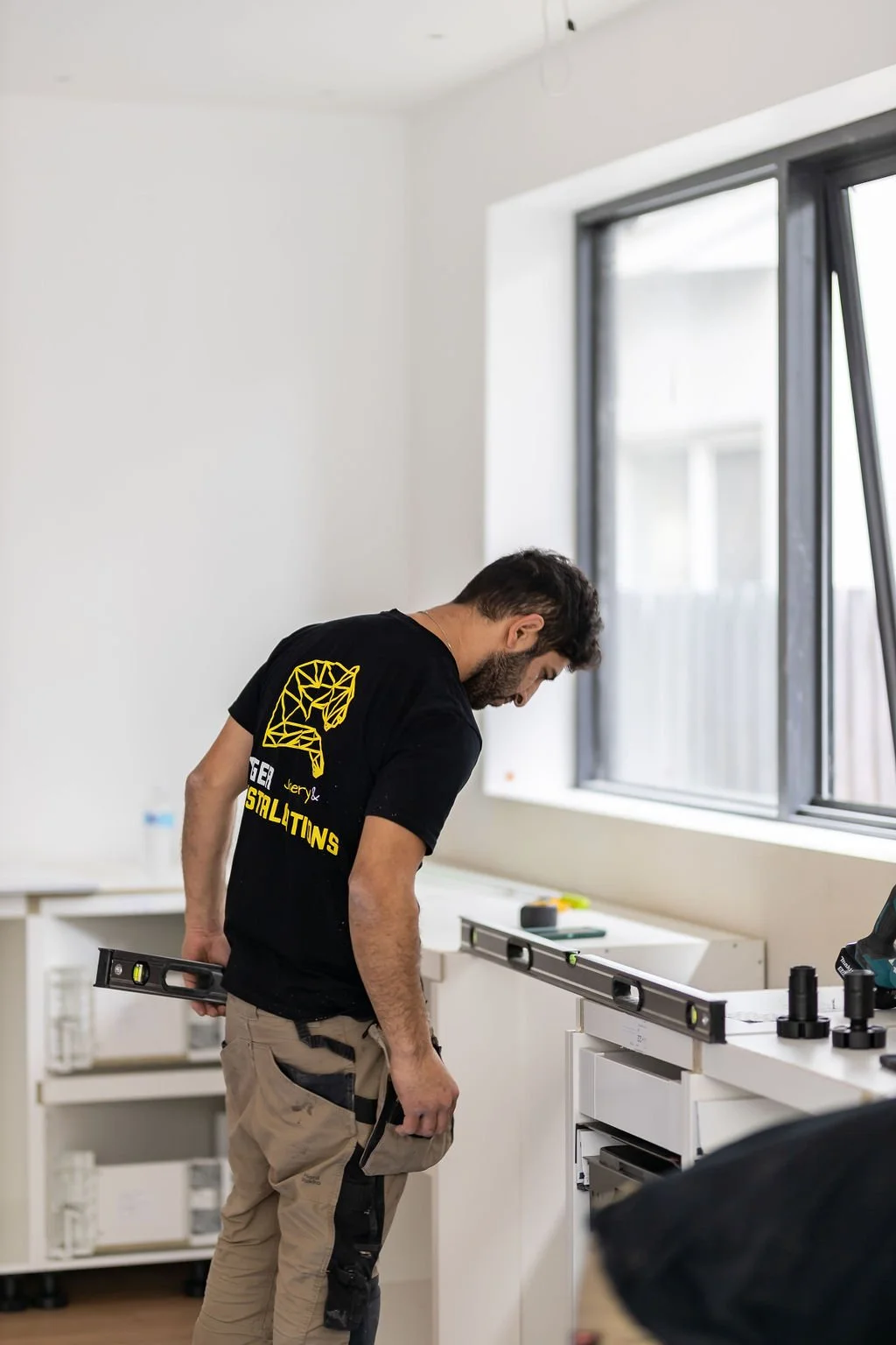 Kitchen and bathroom renovations in Melbourne tradesman installing kitchen cabinets