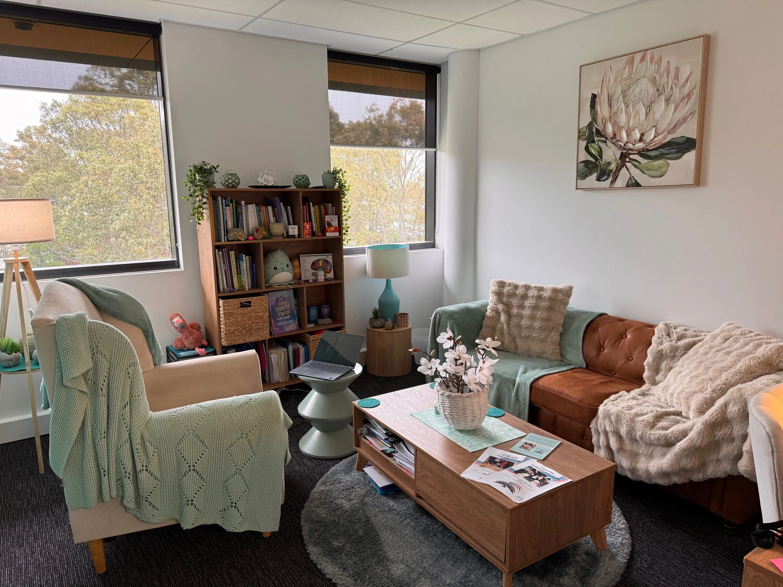 3D figures of a therapist and patient, with the patient lying on an orange couch and the therapist seated in a chair.