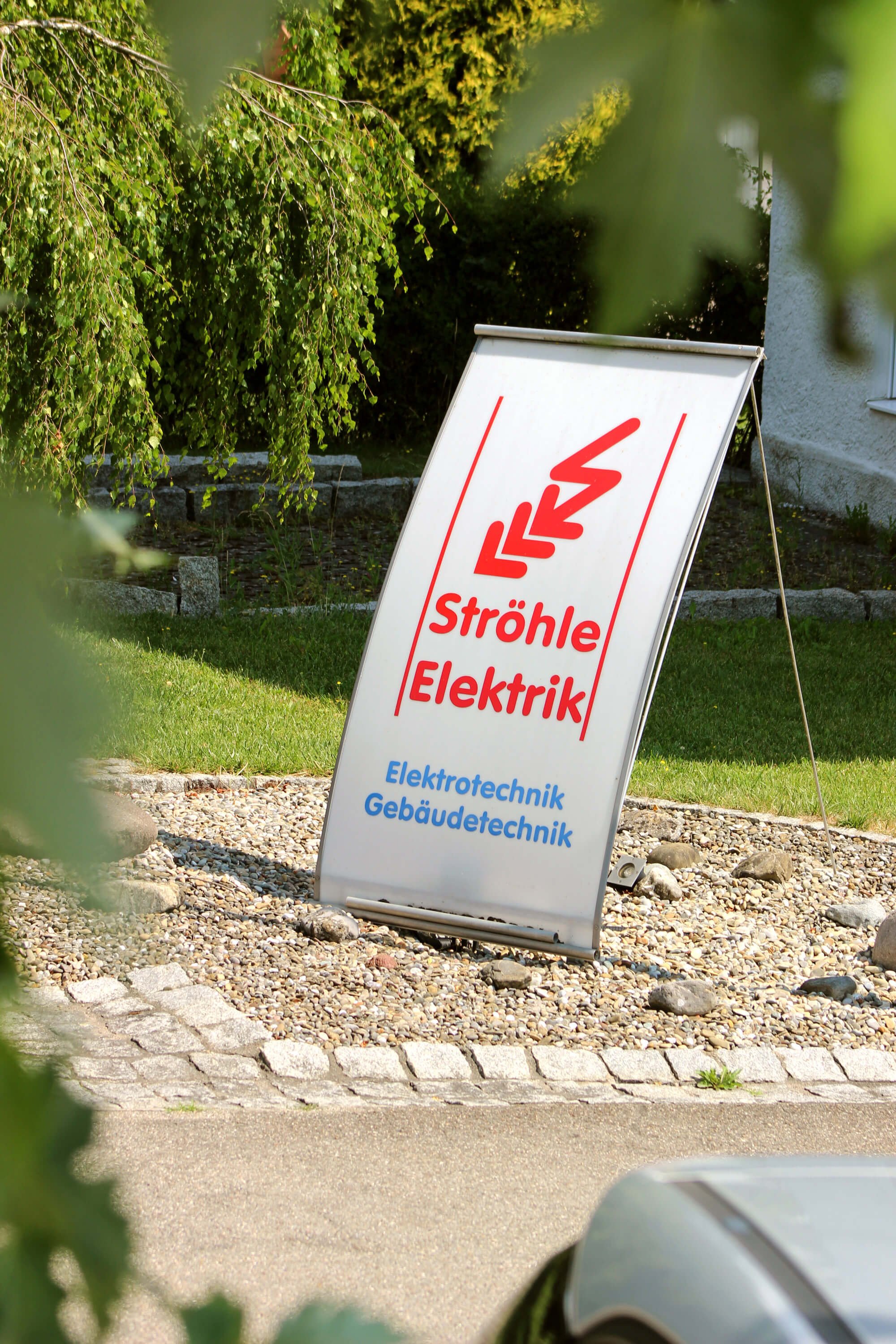 Werbetafel für elektrischen Straßenbahndienst mit Text in Deutsch und einem Logo.