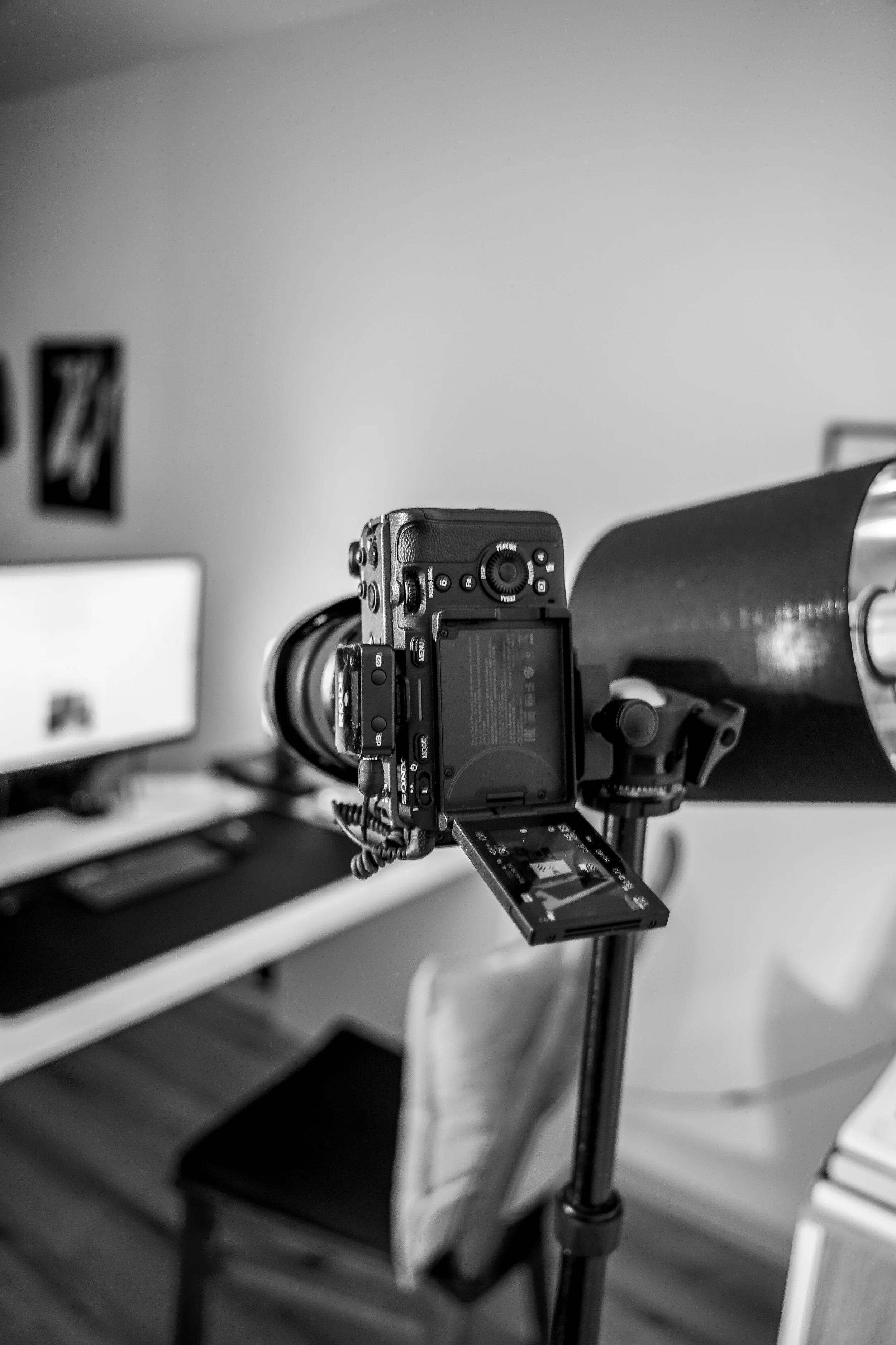 Eine Kamera auf einem Stativ richtet sich auf ein Objekt, in einem Raum mit einem Fernseher und einem Stuhl im Hintergrund.