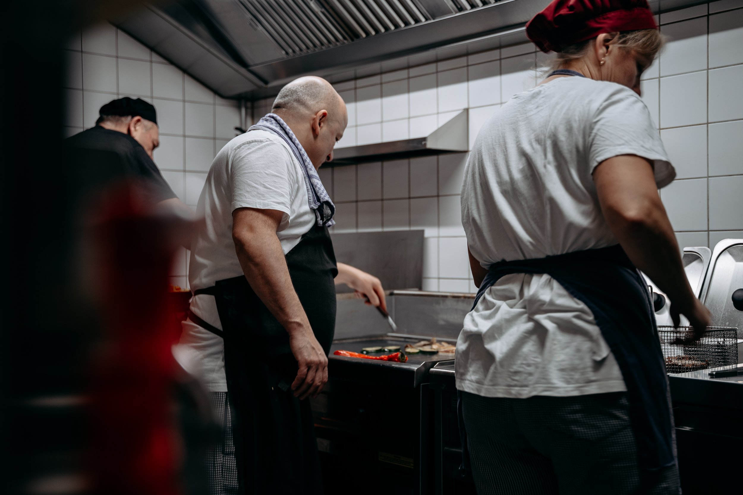 Köche in einer Restaurantküche beim Kochen und Vorbereiten von Speisen.