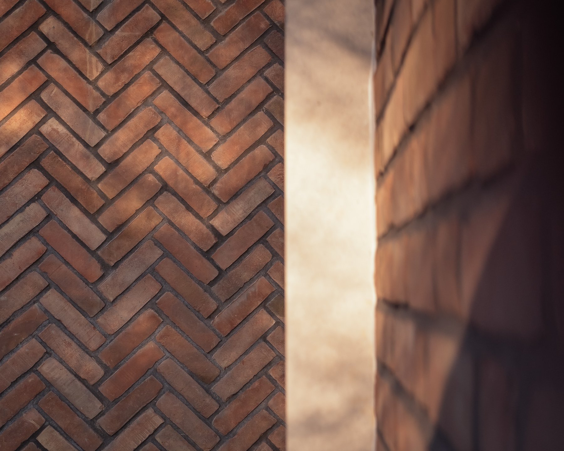 Close-up of a brick wall with a herringbone pattern on the left side and a brick corner on the right side.