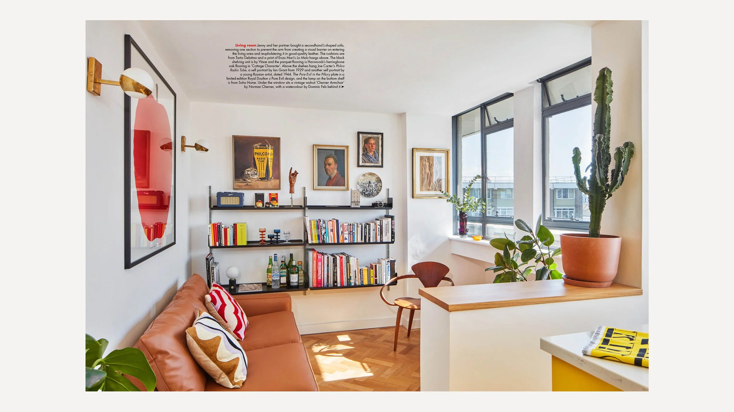 Living room with brown leather sofa, colorful pillows, wall-mounted black bookshelf with books and decor, framed art portraits, large windows with city views, potted cactus, and plants near the window.