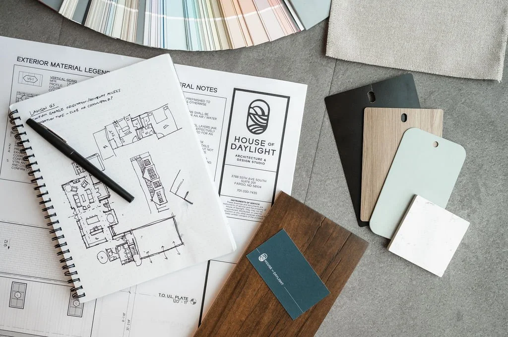 Architectural design materials including sketches, material samples, color palette, and branding for House of Daylight architectural and design studio, laid out on a gray surface.