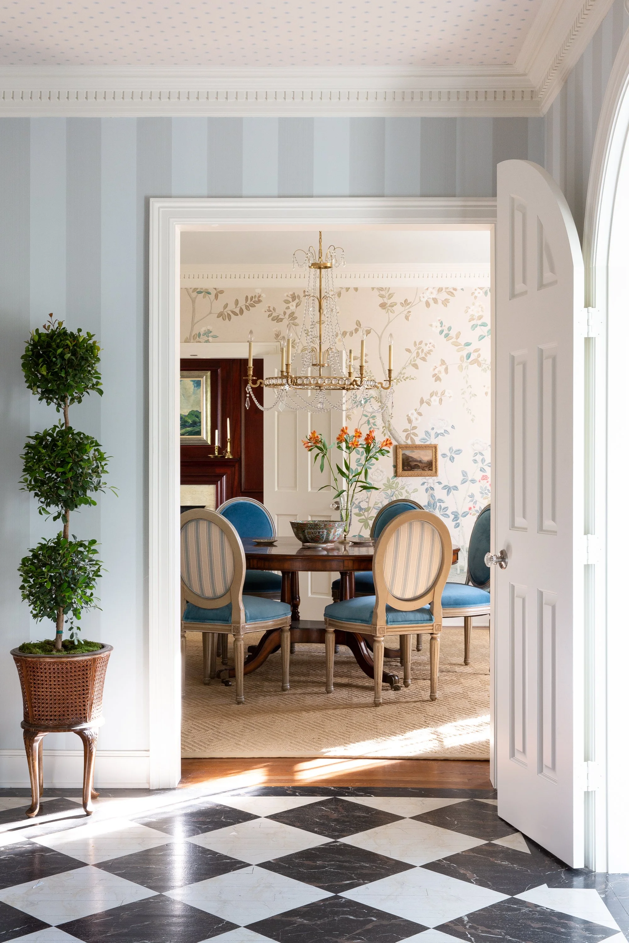 Interior design photography by Jeff Jones featuring a vestibule with Mark Sikes style, Southern Living inspiration, painted faux wood tile, Schumacher wallpaper, and boxwood topiary in Waco, Texas.