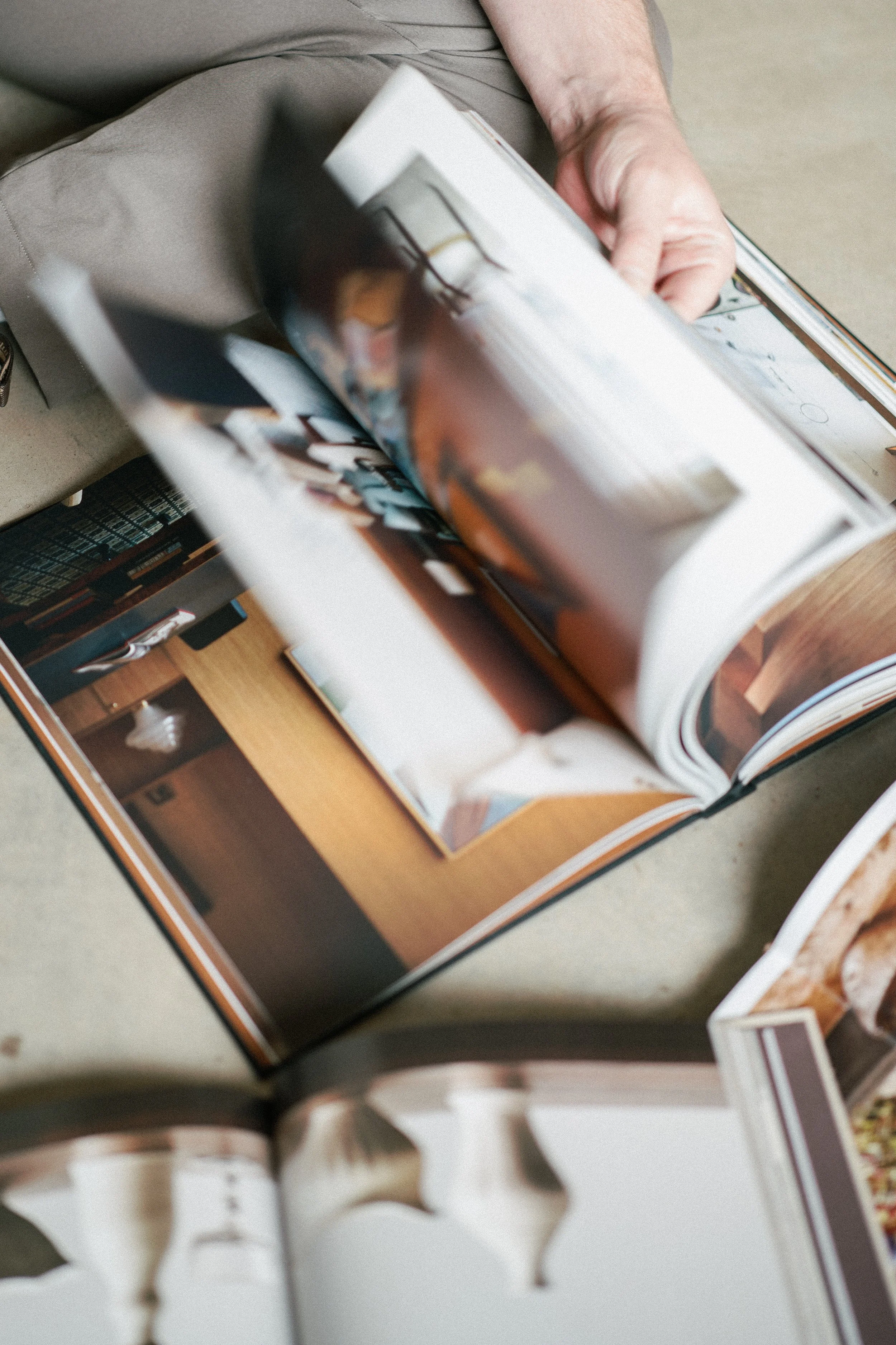 Person turning the pages of an open interior design magazine showing pictures of rooms and decor.