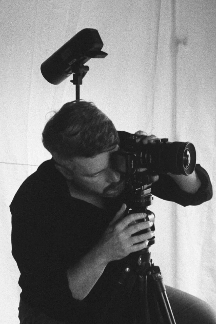 Jeff Jones of Jeff Jones Photography is working with a professional video camera mounted on a tripod in a black and white setting.