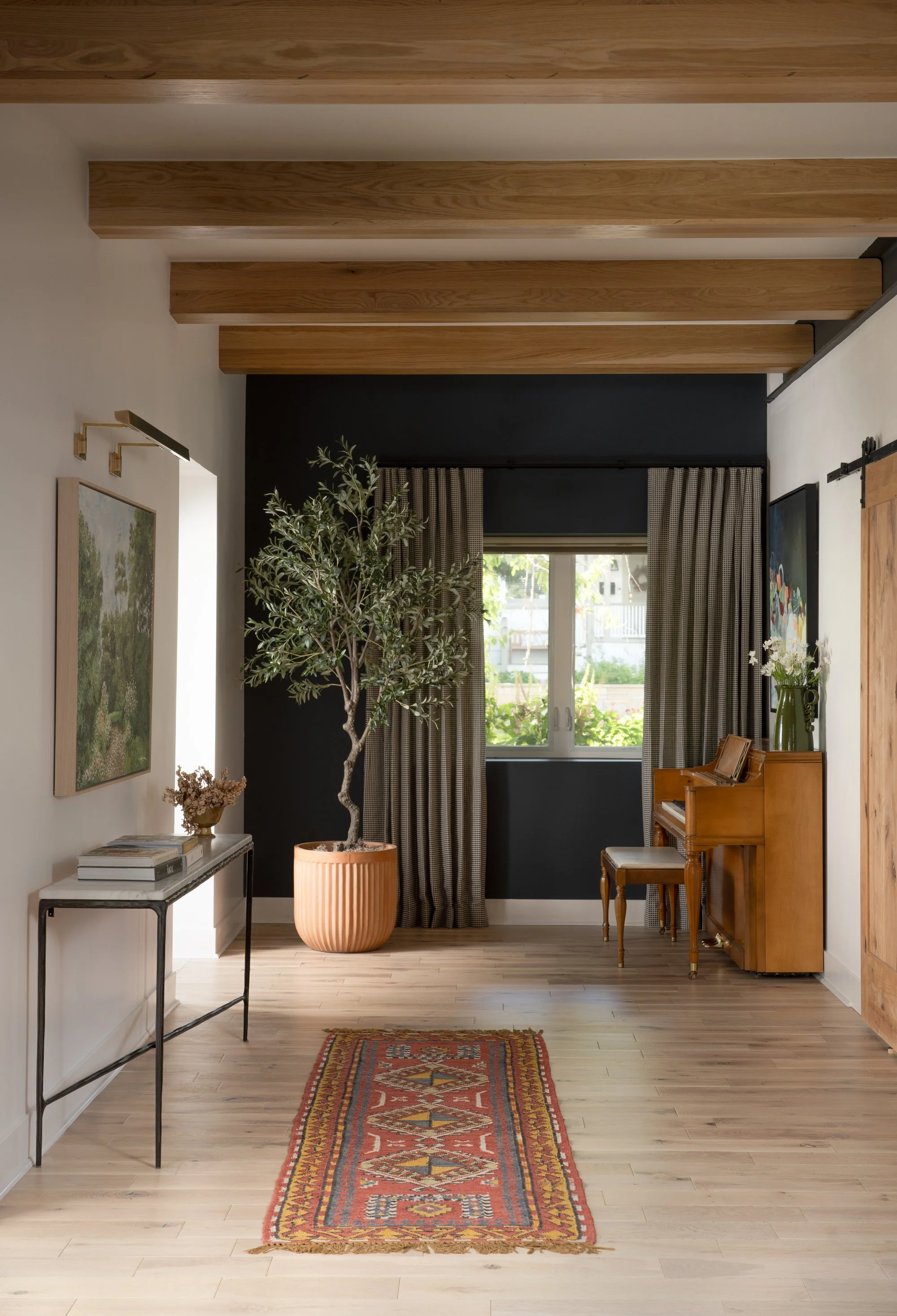 Warm modern hallway with wood beams, natural light, a vintage rug, and a potted olive tree. Interior design photography by a Texas-based interior design photographer, Jeff Jones